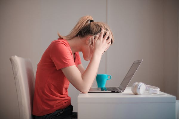 In this image woman sitting in laptop shes looking in stress